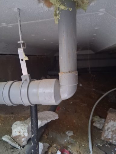 verstopping onder de vloer Grijze pvc-buizen en leidingen in een donkere kelderruimte.